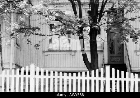 Foto in bianco e nero di parte del vecchio, fatiscente, villa in legno con Picket Fence e acero. Foto Stock