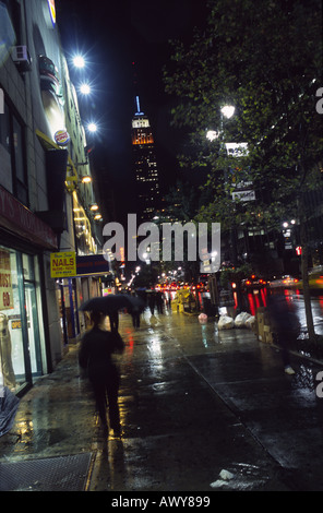 Camminando sotto la pioggia sulla 34th Street verso Empire State Building di New York City Foto Stock