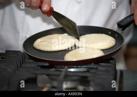 Lo chef girando tradizionali frittelle irlandese in un tegame su un fornello a gas di cottura per la cottura Foto Stock