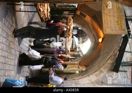 Un uomo porta pane fresco attraverso un mercato nella città vecchia sezione di Gerusalemme Foto Stock