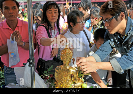 Il fissaggio della foglia oro e preghiere di fronte al Wat Phra Kaeo Grand Palace (il Tempio del Buddha di smeraldo), Bangkok, Thailandia Foto Stock