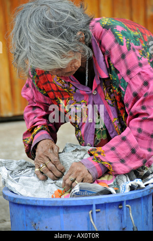 Vecchiaia e povertà: donna ordinando attraverso il cestino in Sukhothai, Thailandia, Sud-est asiatico, in Asia Foto Stock