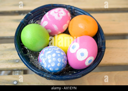 Dipinte a mano e le uova di Pasqua in un blu ciotola di bambù Foto Stock