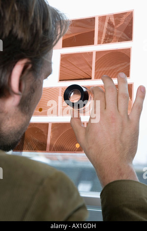 Uomo che guarda uno scorrimento del foglio di contatto Foto Stock