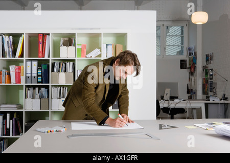 Un uomo appoggiato su di una scrivania e di un disegno Foto Stock