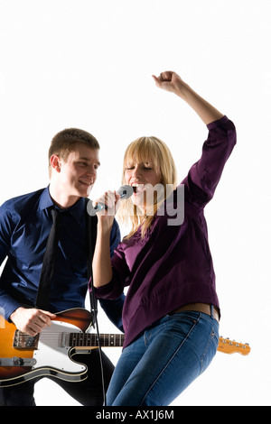 Studio shot di un uomo suonare la chitarra elettrica e una donna cantare in un microfono Foto Stock