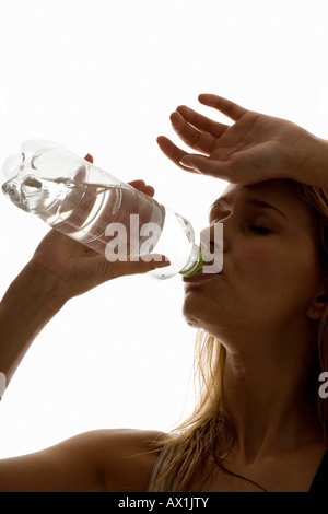 Una sudorazione donna bere da una bottiglia di acqua Foto Stock