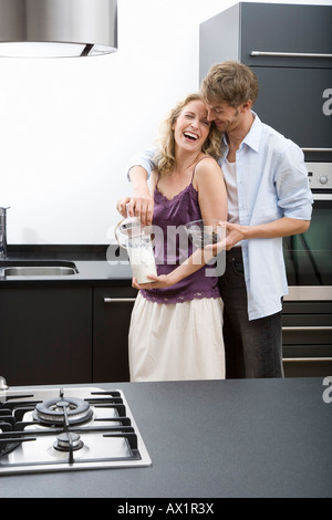 Una metà uomo adulto con le braccia intorno a metà donna adulta di trattenimento di un mixer elettrico Foto Stock