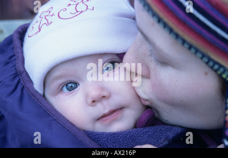 Madre bacia 6 mese-vecchio figlia sulla guancia Foto Stock