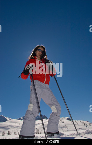 Giovane donna sci, in posa di fronte di un colore blu cielo e paesaggio di montagna Foto Stock