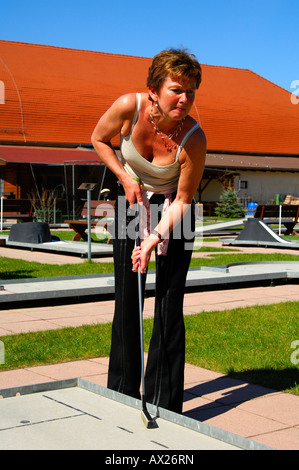 Giovane donna gioca a mini-golf Foto Stock