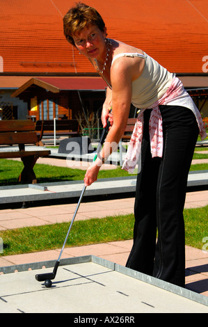 Giovane donna gioca a mini-golf Foto Stock