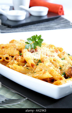 Penne gratinate con pesce e frutti di mare di formaggio grattugiato Foto Stock