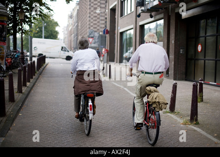 Due persone anziane rideing della bicicletta su un viale tranquillo Foto Stock