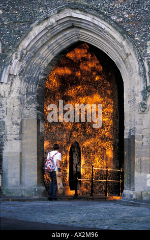 Alla luce di un guidatore di skateboard passeggiate attraverso un arco medievale in St Albans Foto Stock