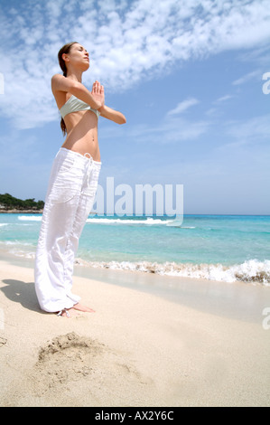 Spiaggia Benessere giovane donna facendo un esercizio di yoga benessere benessere wellness serena montare vitalità fitness Foto Stock