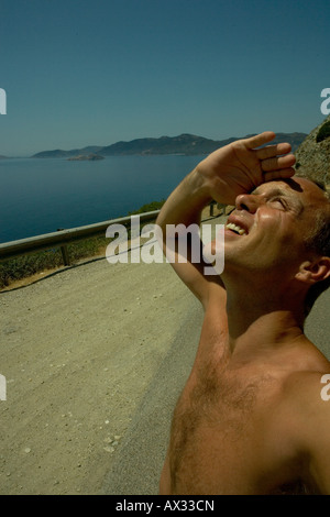 Giovane uomo che copre la sua gli occhi e guarda il sole Foto Stock