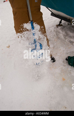 Un uomo di Trapani un foro attraverso uno spesso strato di ghiaccio con manuale coclea di ghiaccio Foto Stock