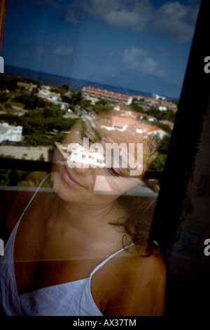 Giovane donna guardando fuori della finestra al mattino Foto Stock
