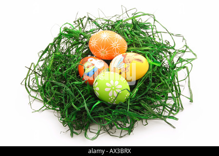 Quattro uova di pasqua in un nido isolato su bianco Foto Stock