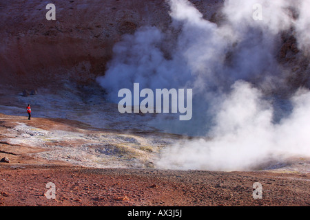 Un uomo si erge sul bordo di una sensuale e fumatori caldera vulcanica nel Altiplano della Bolivia. Foto Stock