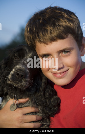 Giovane ragazzo sorridente e coccole il suo cocker spaniel cane, ritratto Foto Stock