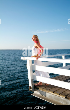 Moda giovane donna in mare in piedi su un ponte sull'oceano Foto Stock