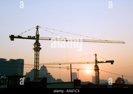 Cina, Pechino. Tramonto su un sito di costruzione di gru. Foto Stock