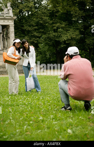 Uomo di scattare una foto di due donne asiatiche in un parco Foto Stock