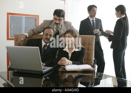 Tre uomini di affari che lavora su un computer portatile in un ufficio Foto Stock