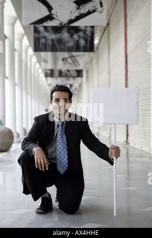 Ritratto di un imprenditore che mostra un cartello nel mercato Foto Stock