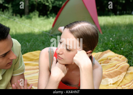 Coppia giovane sdraiato sul prato di fronte ad una tenda Foto Stock