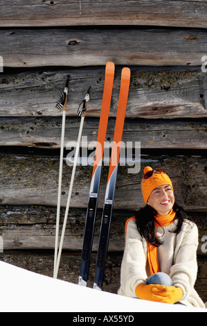 Giovane donna seduta di fronte a capanna alpina Foto Stock