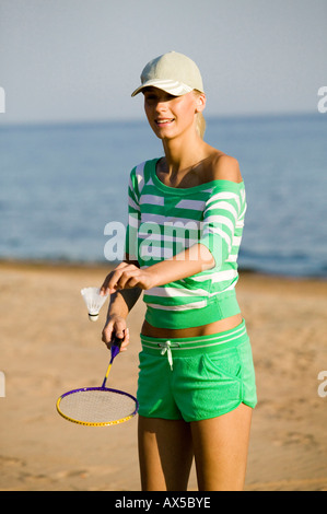 Giovane donna giocando badminton sulla spiaggia Foto Stock
