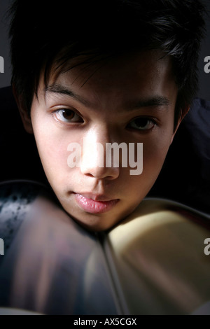 Giovane uomo che poggia il mento su una rivista Foto Stock