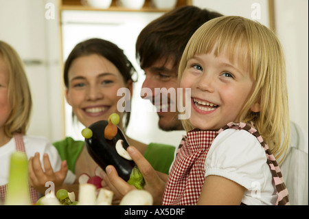 I genitori con bambini (4-5) giocando in cucina, sorridente Foto Stock