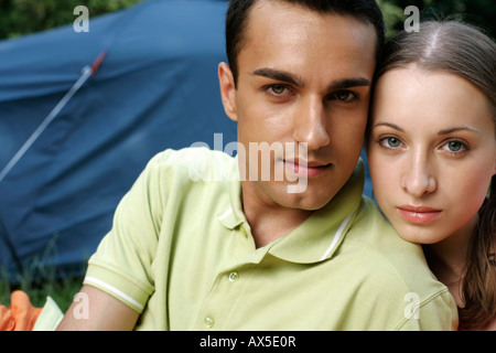 Ritratto di una giovane coppia seduta strettamente insieme davanti a una tenda Foto Stock