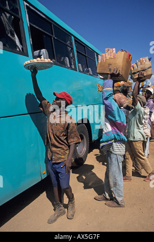 Giovani uomini che lavorano come ambulanti tentare di vendere i rinfreschi per passeggeri di un autobus, Moshi, Tanzania. Foto Stock