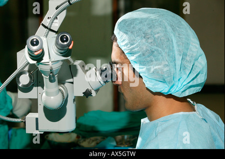 Medico guardando attraverso un microscopio durante la chirurgia della cataratta in PIETERMARITZBURG, Sud Africa e Africa Foto Stock