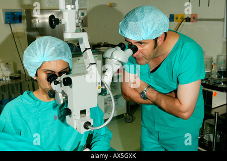 Medico guardando attraverso un microscopio durante la chirurgia della cataratta in PIETERMARITZBURG, Sud Africa e Africa Foto Stock