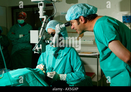 Medico guardando attraverso un microscopio durante la chirurgia della cataratta in PIETERMARITZBURG, Sud Africa e Africa Foto Stock