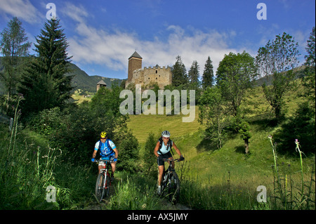 Motociclisti di montagna maschili e femminili in bicicletta di fronte al Castello di Reinegg vicino a Sarnthein, Sarentino, Bolzano, Italia, Europa Foto Stock