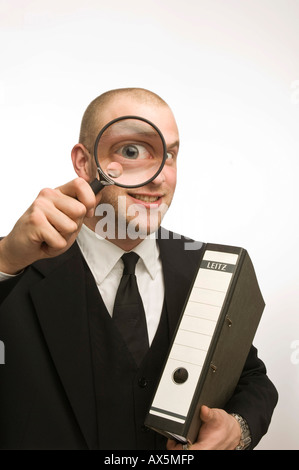 Giovane uomo che porta azienda legante di lente di ingrandimento nella parte anteriore del suo volto Foto Stock