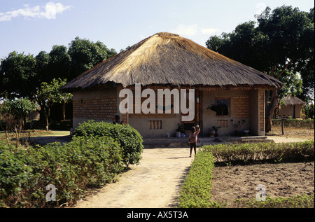 Lusaka, Zambia, Africa. Un ragazzo onde provenienti dalla parte anteriore della sua ordinata la casa e il giardino. Foto Stock