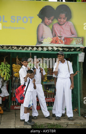 I bambini vestiti in uniformi di scuola alla fermata dell autobus, Godagama, Sri Lanka, Sud Asia Foto Stock