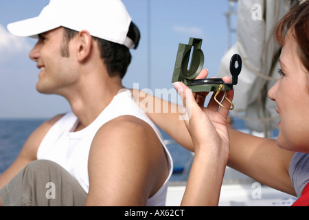 Donna mettendo la mano sull'uomo della spalla, utilizzando una bussola Foto Stock
