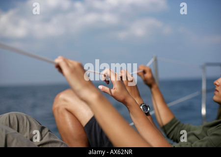 Giovane Azienda in una linea di sicurezza a bordo di una barca a vela Foto Stock