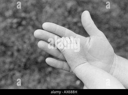 Una madre la mano supporta il minuscolo piede del suo bimbo di due mesi. Foto Stock