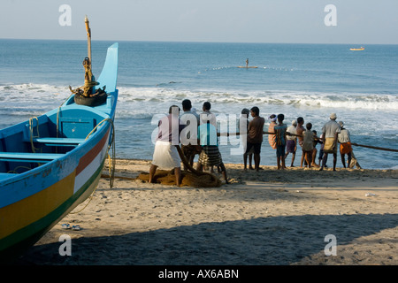 Gli uomini tirando in reti da pesca sulla spiaggia di Varkala India Foto Stock