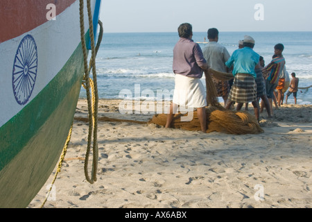 Gli uomini tirando in reti da pesca sulla spiaggia di Varkala India Foto Stock